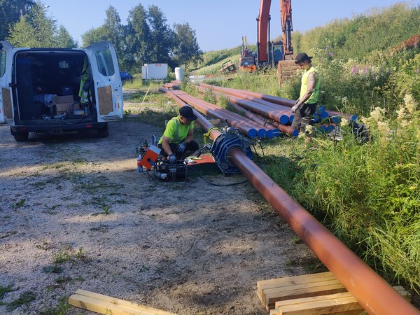 Asentajat puskuhitsaamassa muoviputkilinjaa työmaalla