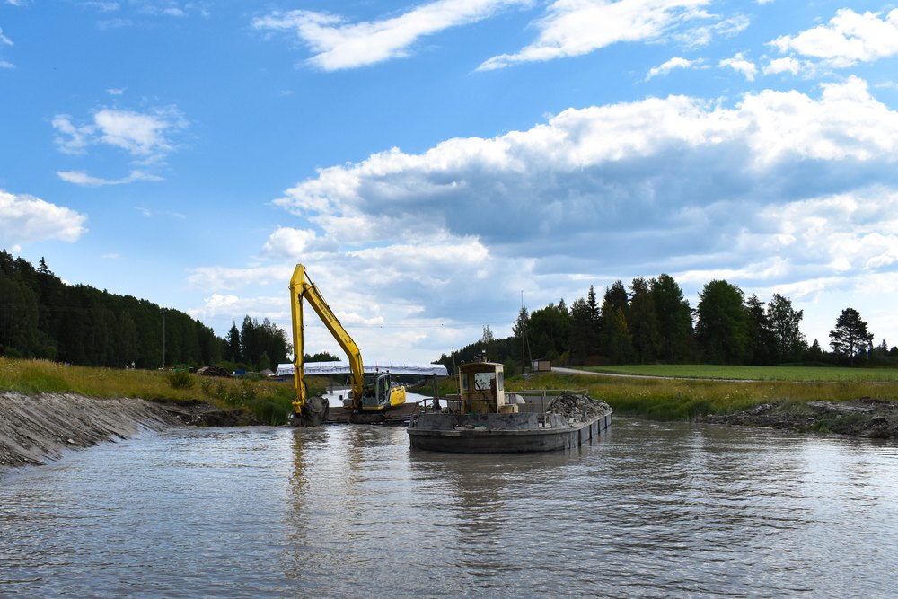 Kelluva kaivinkone työlautalla joessa